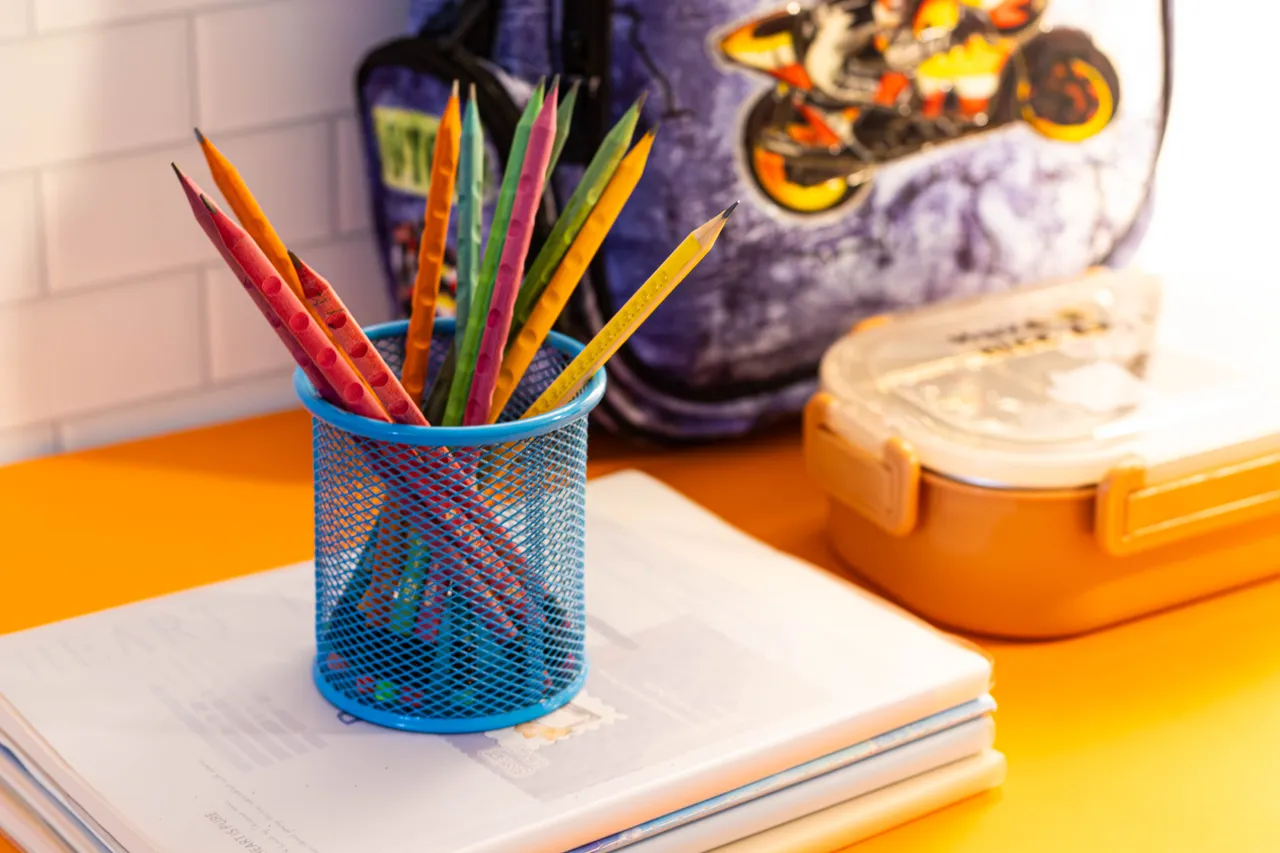 Pot de crayons colorés et fournitures scolaires posés sur un bureau