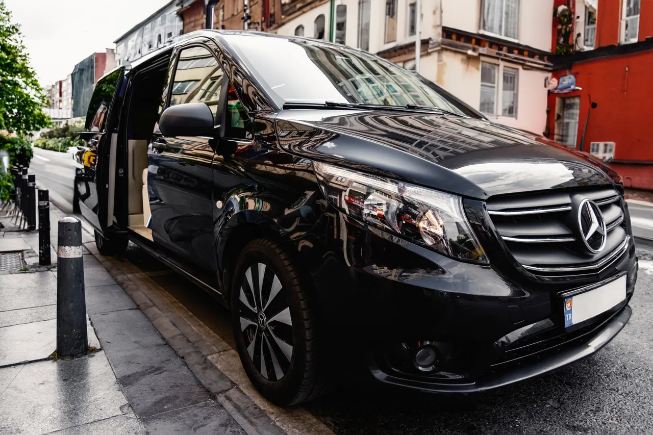 Van noir stationné en ville avec sa porte latérale ouverte