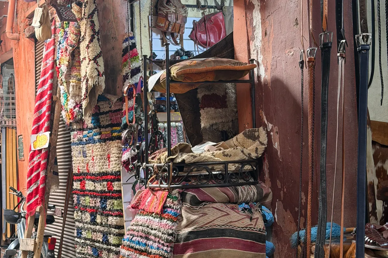 Textiles et articles en cuir exposés dans une rue du souk de Marrakech