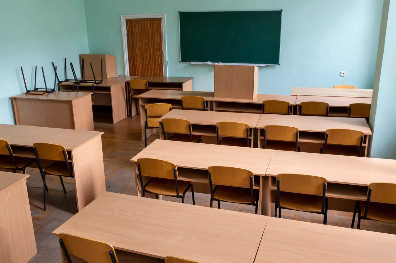 Salle de classe vide avec rangées de bureaux et tableau vert