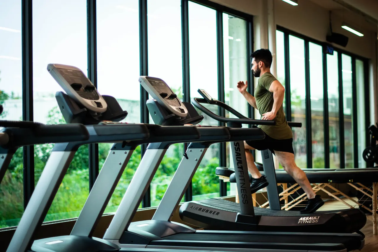 Personne courant sur un tapis dans une salle de sport lumineuse
