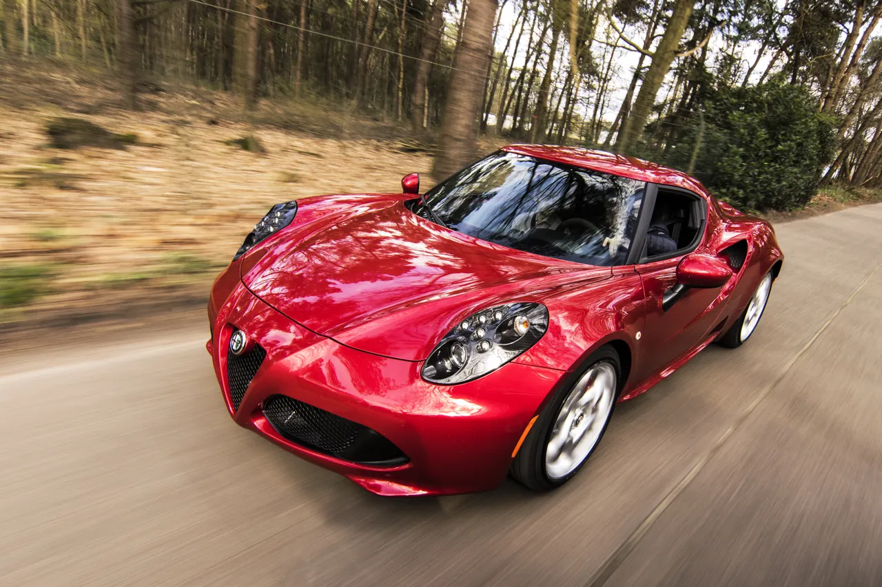 Voiture sportive rouge sur une route bordée d’arbres
