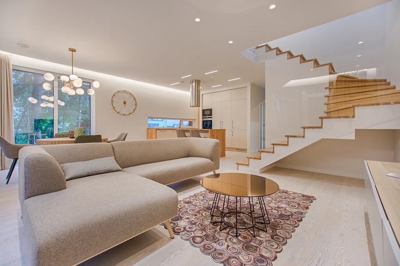 Salon lumineux avec canapé, fauteuil et escalier intérieur
