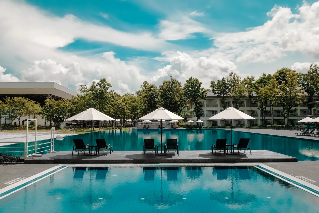 Piscine d’un établissement hôtelier entourée de parasols et de végétation