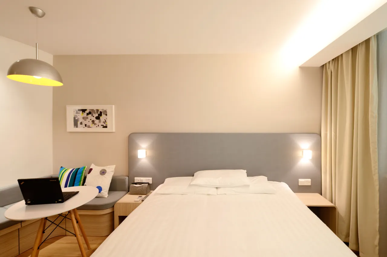 Chambre avec un lit double, un bureau et des rideaux clairs