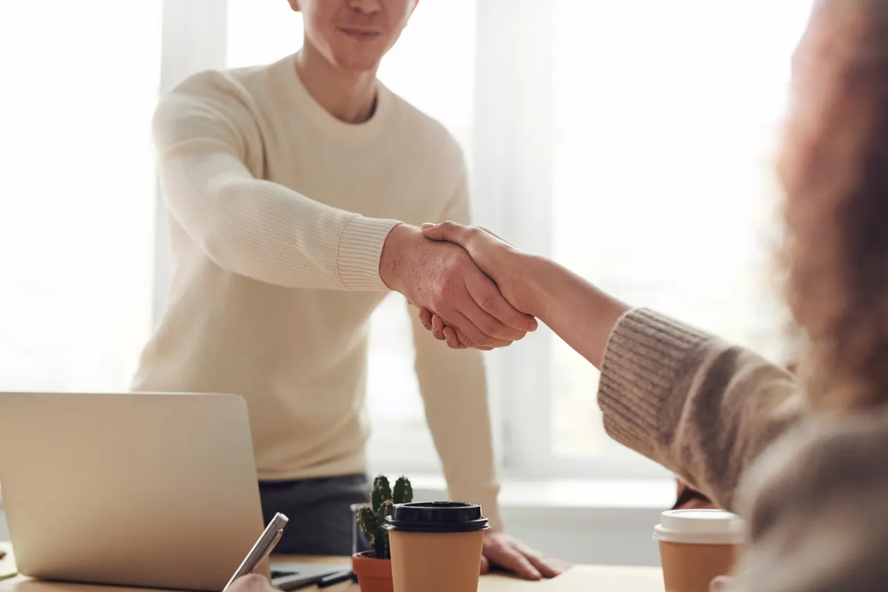 Poignée de main entre deux personnes autour d’une table de travail